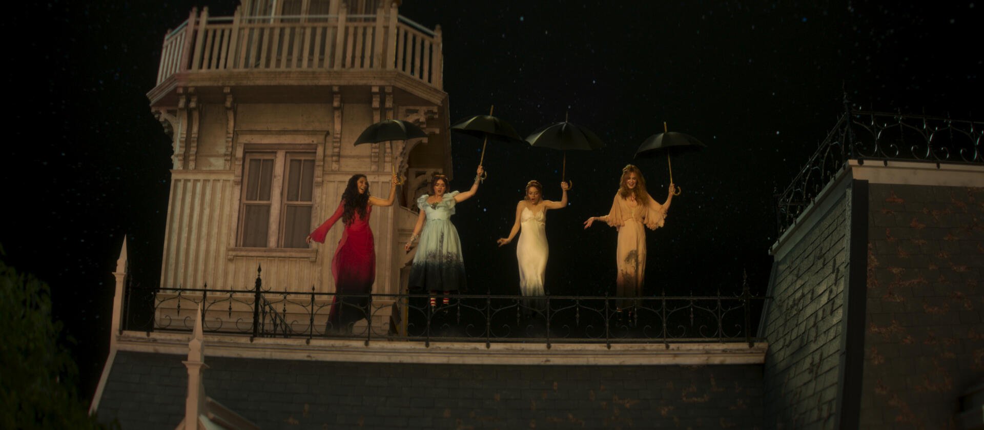 Practical Magic 2 wallpaper: four witches on a stage-like rooftop, women holding umbrellas against a starry night — 2K Quad HD PC desktop background.