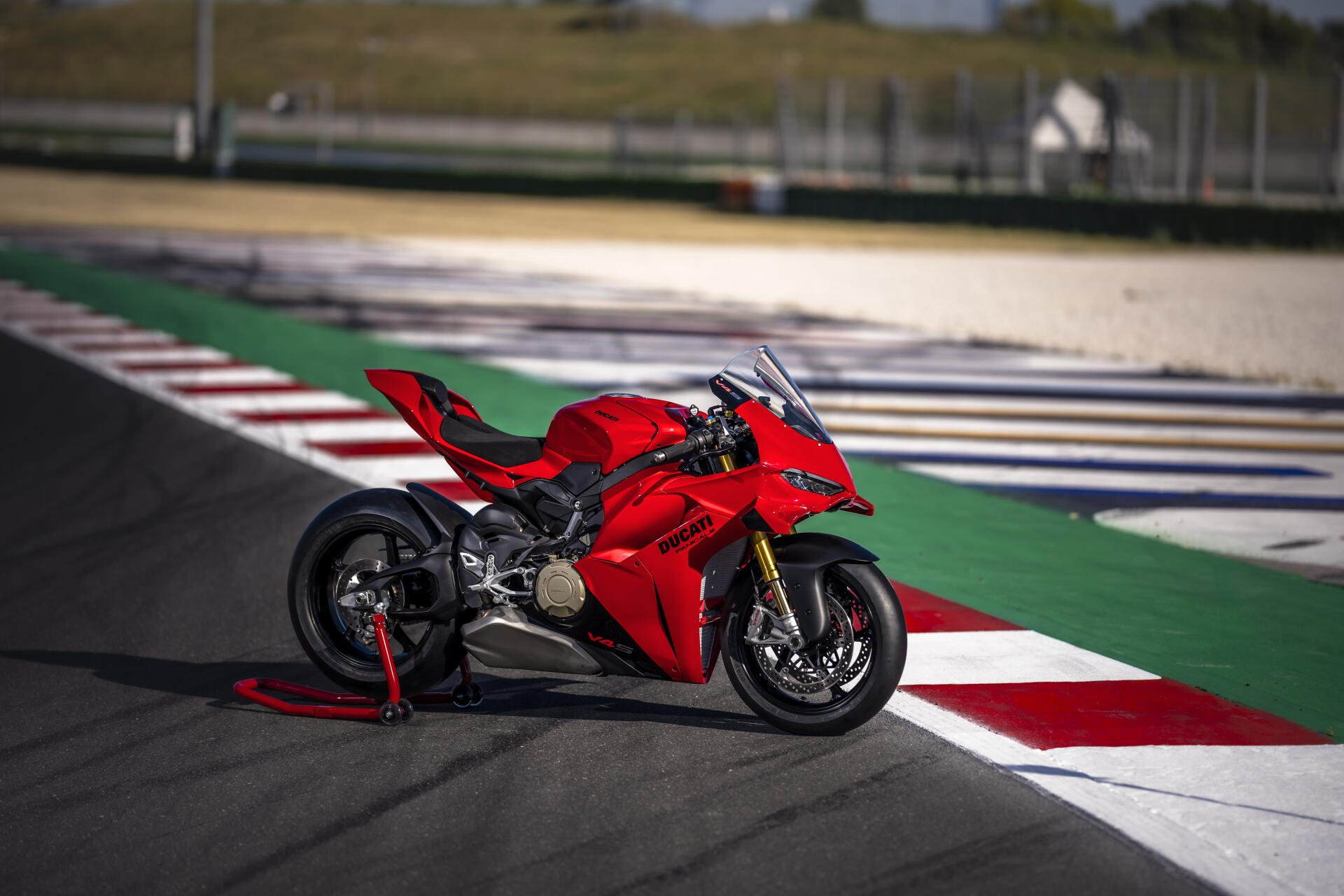 Red Ducati Panigale V4 sport motorcycle on a race track, featured in an 8K Ultra HD PC desktop wallpaper.