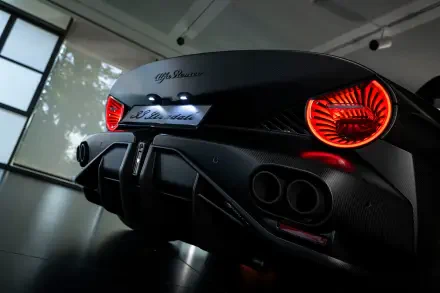 Rear view of a black Alfa Romeo 33 Stradale sports car with glowing red circular taillights, displayed as an 8K Ultra HD PC desktop wallpaper background.