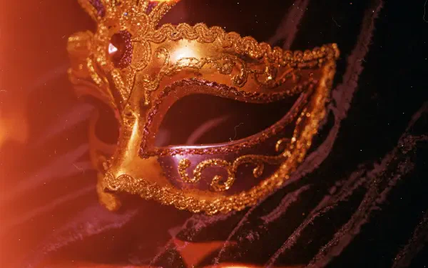 Gold filigree Mardi Gras mask with purple accents against dark, glittering bokeh — 4K Ultra HD PC desktop wallpaper background.