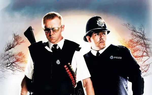 Hot Fuzz 4K Ultra HD PC desktop wallpaper: two stern uniformed police officers—one wearing sunglasses with shotgun-shell bandolier, dramatic sky and silhouetted trees.