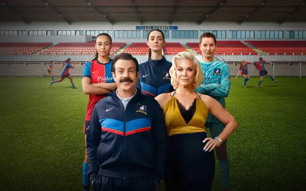 4K Ultra HD PC desktop wallpaper featuring a mustachioed soccer coach with three players on a stadium pitch; image tagged Ted Lasso.
