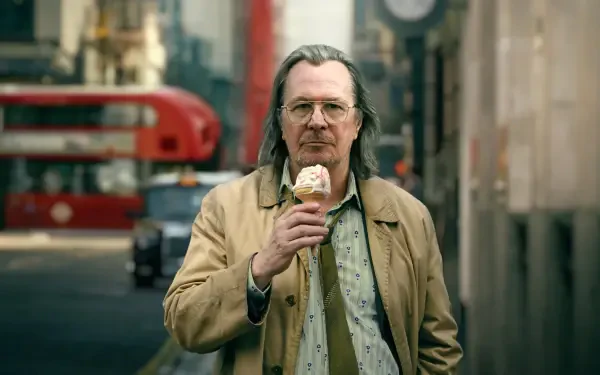 Slow Horses 4K Ultra HD PC desktop wallpaper and background: man in beige coat eating an ice cream on a London street with a blurred red double-decker bus behind him.
