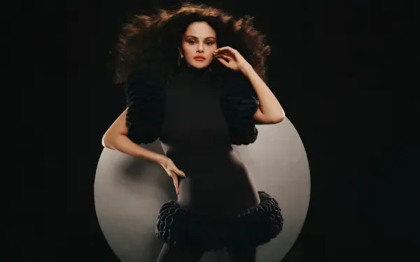 Glamorous female pop singer portrait in a dramatic black outfit with voluminous hair against a dark circular backdrop — 5K Ultra HD PC desktop wallpaper, celebrity music theme.