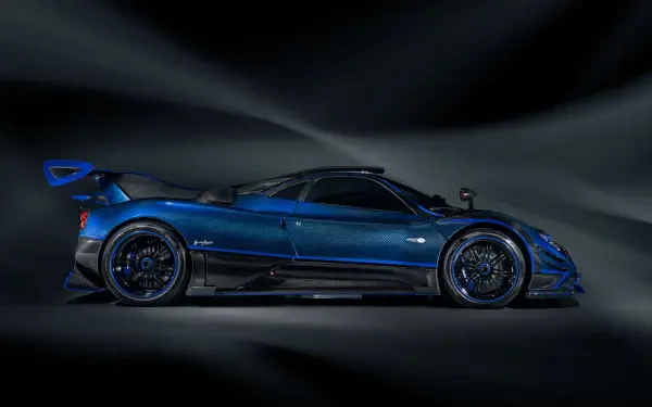 Side profile of a blue Pagani Zonda racing car with aerodynamic wings and carbon accents against a dark, streaked background — 4K Ultra HD PC desktop wallpaper.