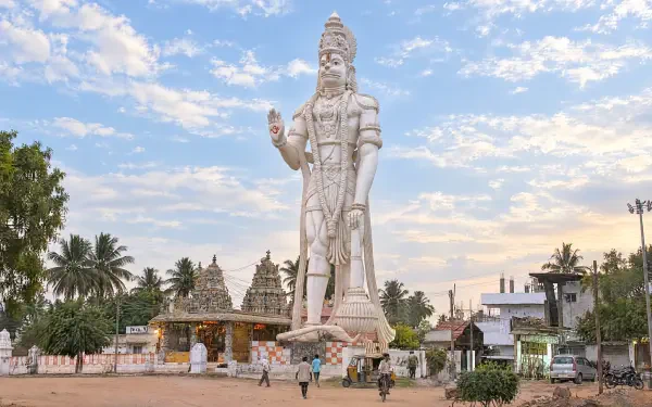 Giant Lord Hanuman statue before a Hindu temple, ornate white sculpture and palm trees under a blue sky — 4K Ultra HD PC desktop wallpaper and background.