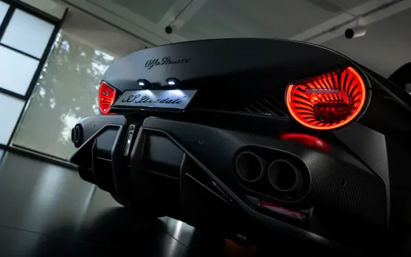 Rear view of a black Alfa Romeo 33 Stradale sports car with glowing red circular taillights, displayed as an 8K Ultra HD PC desktop wallpaper background.