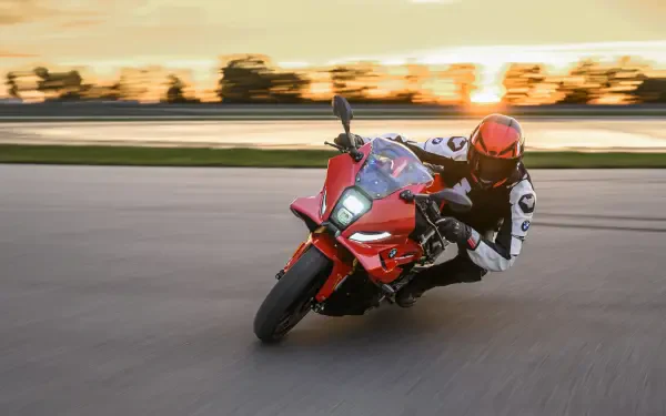 BMW F 450 RR motorcycle racer leaning through a track turn at sunset, 8K Ultra HD PC desktop wallpaper background.