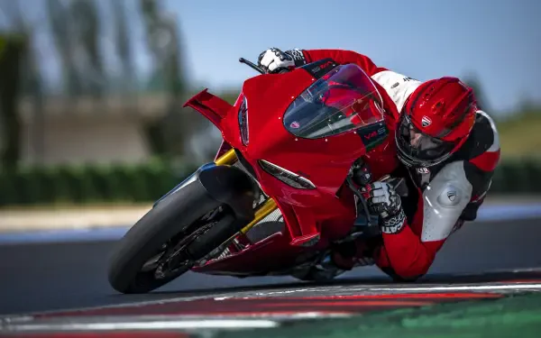 Ducati Panigale V4 and motorcyclist leaning into a racetrack turn, 8K Ultra HD desktop wallpaper background.
