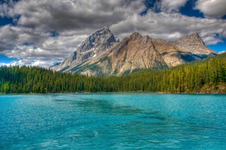 A stunning view of the Canadian Rockies, featuring towering mountains and a serene, turquoise lake surrounded by lush forests, showcasing the beauty of nature. HD desktop wallpaper.