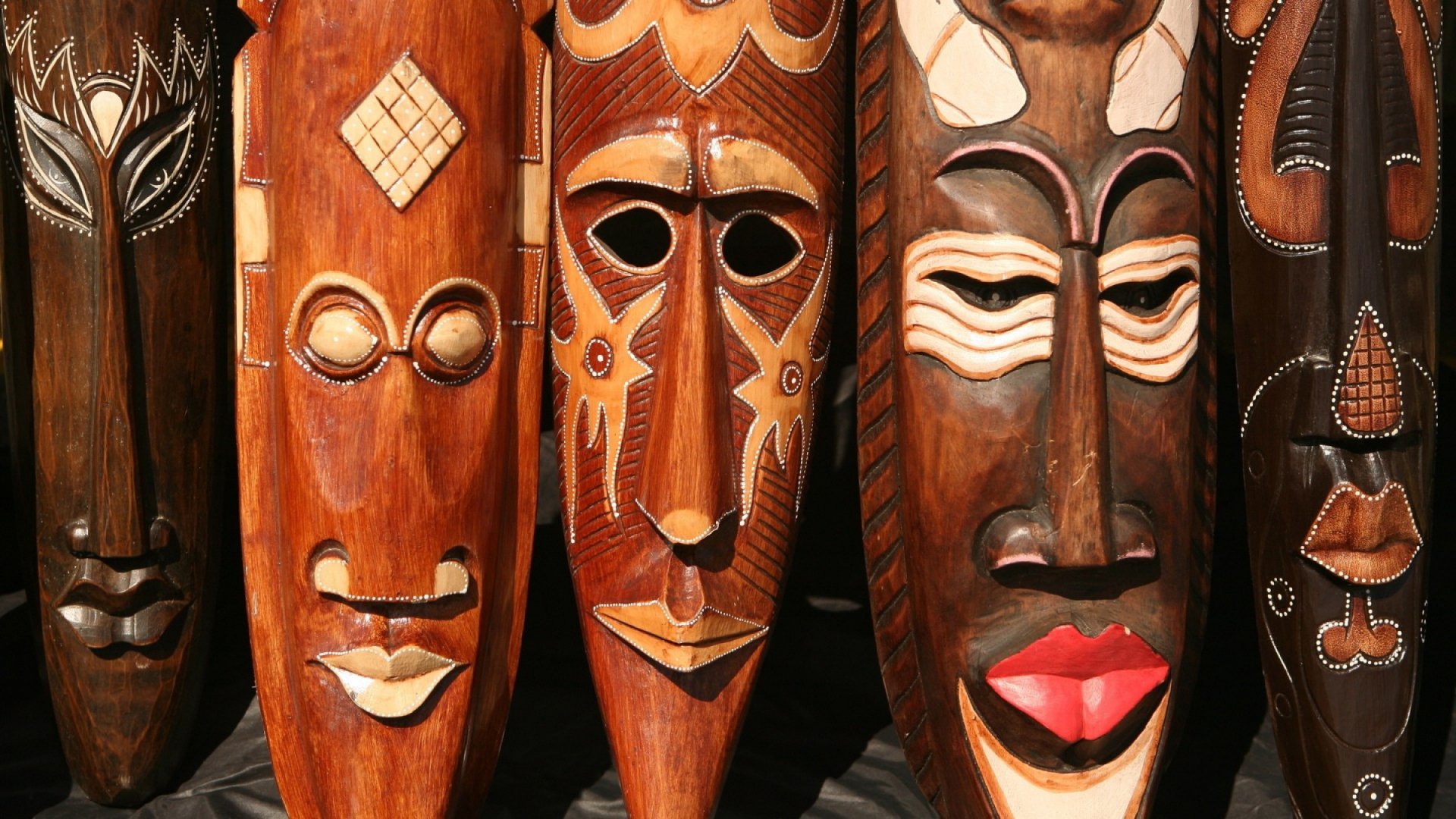 HD desktop wallpaper featuring detailed wooden African face carvings and masks, showcasing traditional craftsmanship and rich cultural artistry.