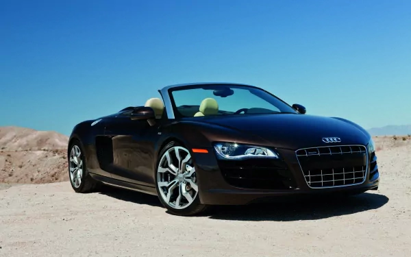 HD desktop wallpaper featuring a black Audi R8 V10 convertible parked on a desert landscape under a clear blue sky.
