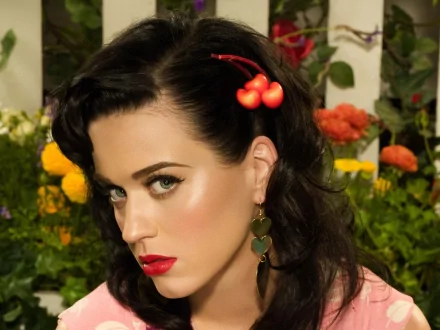 Katy Perry is featured in this vibrant HD desktop wallpaper, showcasing her iconic style against a backdrop of colorful flowers, emphasizing her bold makeup and playful accessories.