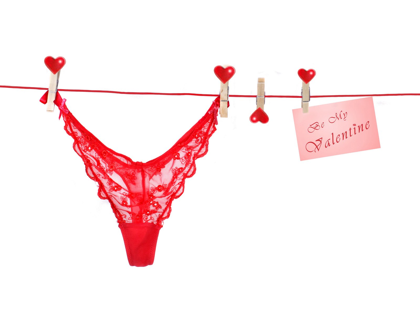 A playful and artistic depiction of love features red lace lingerie hanging on a clothesline, accompanied by a pink card that reads Be My Valentine, set against a bright white background.