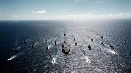 A military fleet of ships sails in formation across the ocean under a clear sky, captured in an HD PC desktop wallpaper and background.