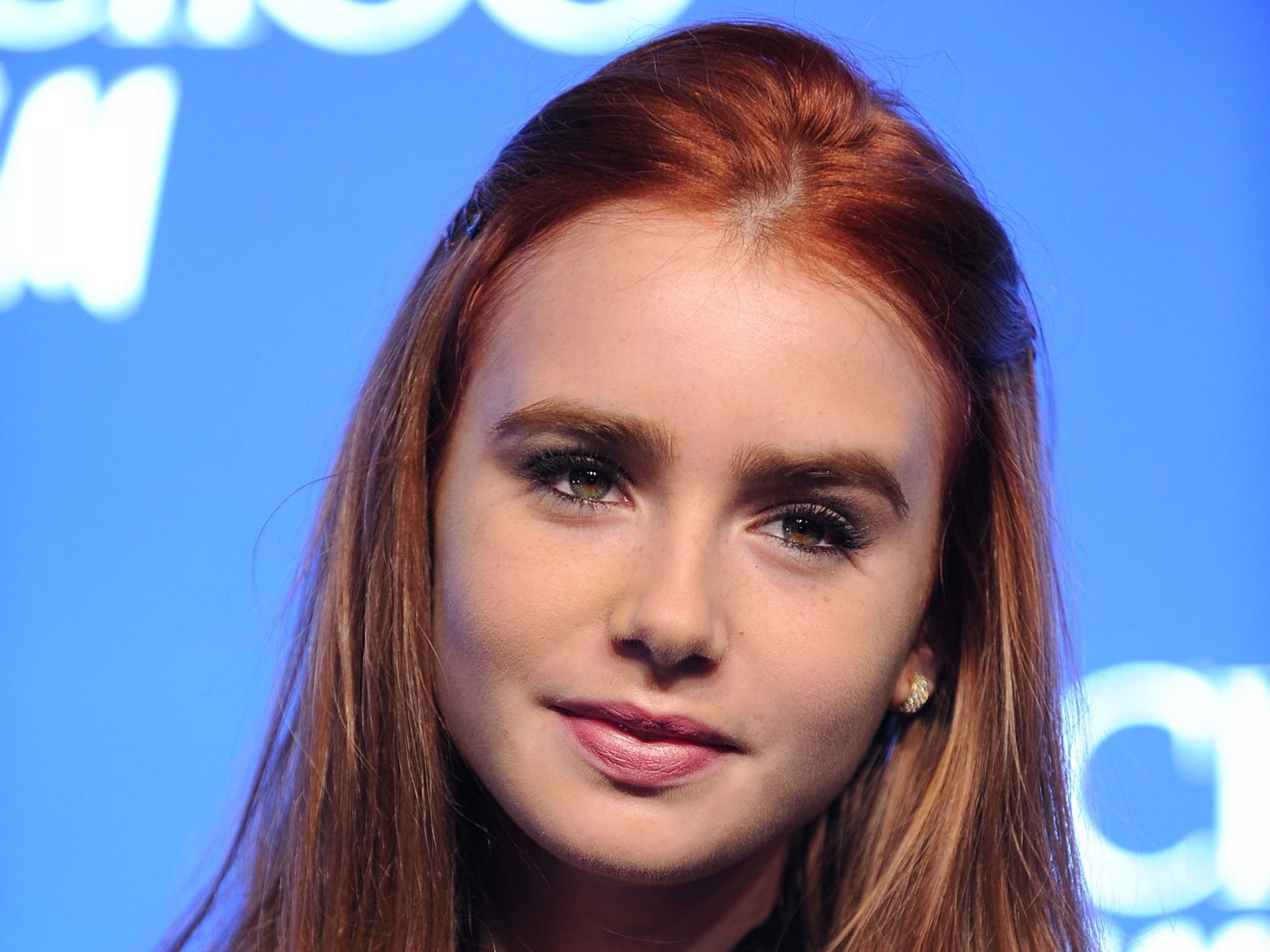 HD PC desktop wallpaper featuring a close-up of celebrity Lily Collins with red hair against a soft blue background.
