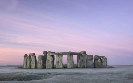 A stunning HD wallpaper of Stonehenge, the historic man-made monument in England, featuring boulders against a serene, pastel sky at dawn.