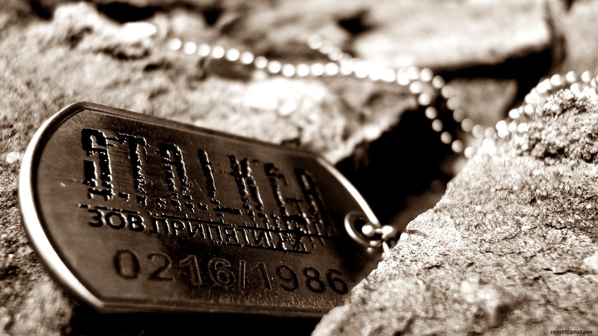 A detailed black and white image of a S.T.A.L.K.E.R. dog tag resting on rocky terrain, capturing the essence of the video game's atmosphere in a striking HD wallpaper.