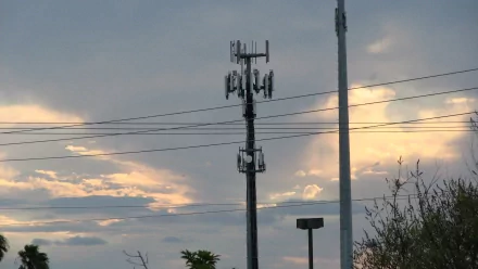 2K Quad HD PC desktop wallpaper: moody sky at dusk with layered clouds, a silhouetted cell tower and power lines, foliage along the horizon.