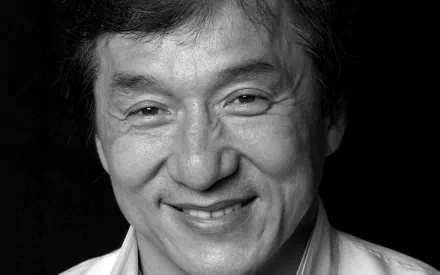 Black and white HD desktop wallpaper featuring a smiling Jackie Chan against a dark background.