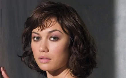 A striking HD wallpaper featuring celebrity Olga Kurylenko, showcasing her captivating gaze and stylish hairstyle against a softly lit background.