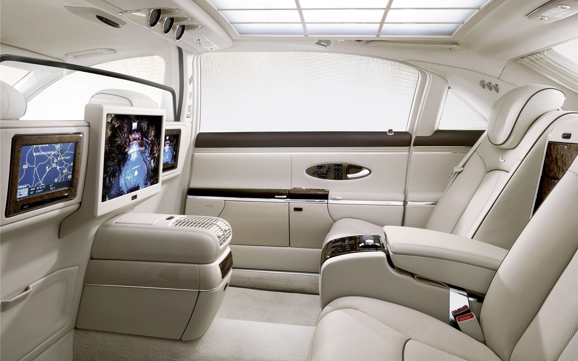 Close-up HD PC desktop wallpaper showing the luxurious interior of a vehicle with cream leather seats and built-in entertainment screens.