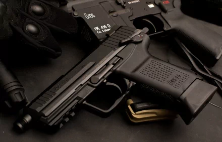 Close-up of a Heckler & Koch pistol resting on a dark surface, showcased in 4K Ultra HD quality as a man-made desktop wallpaper and background.