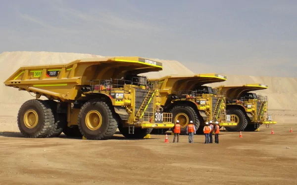 HD wallpaper of large yellow mining trucks parked in a desert environment, with six workers standing nearby.