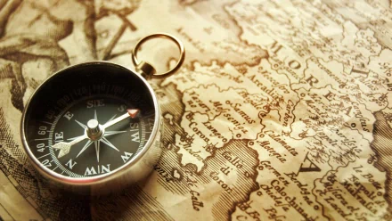 A vintage compass rests on an antique map, highlighting geographical details. This HD image serves as an engaging desktop wallpaper and background.