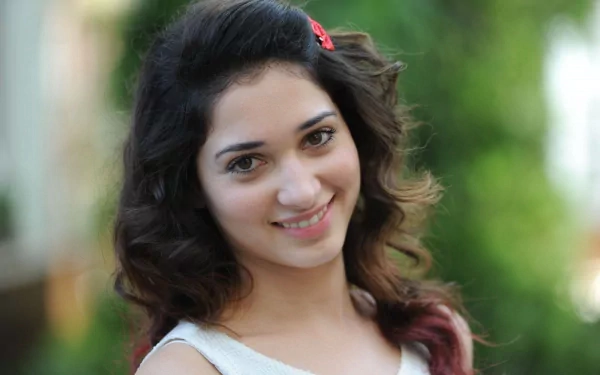 HD desktop wallpaper of a smiling female celebrity with wavy dark hair in a white top, soft blurred green background.