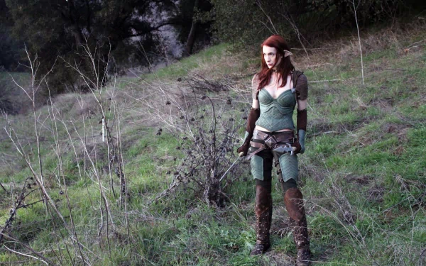 A woman in cosplay stands confidently in a lush green landscape, showcasing her detailed costume. This HD image serves as a striking desktop wallpaper or background.