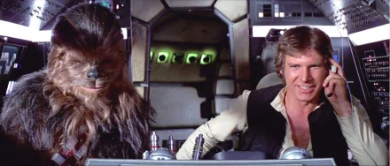 Chewbacca and Han Solo, portrayed by Harrison Ford, sit together in the cockpit of the Millennium Falcon in this vibrant Star Wars HD desktop wallpaper.