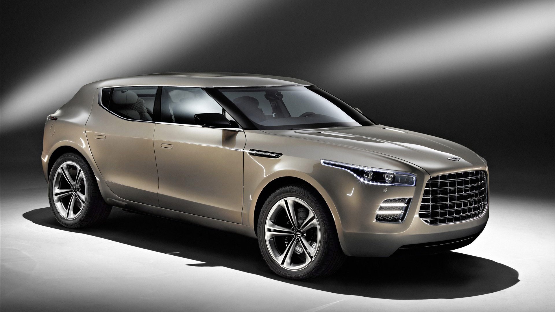 Metallic-beige Aston Martin Lagonda SUV concept under dramatic studio lighting, presented as an HD PC desktop wallpaper and background.