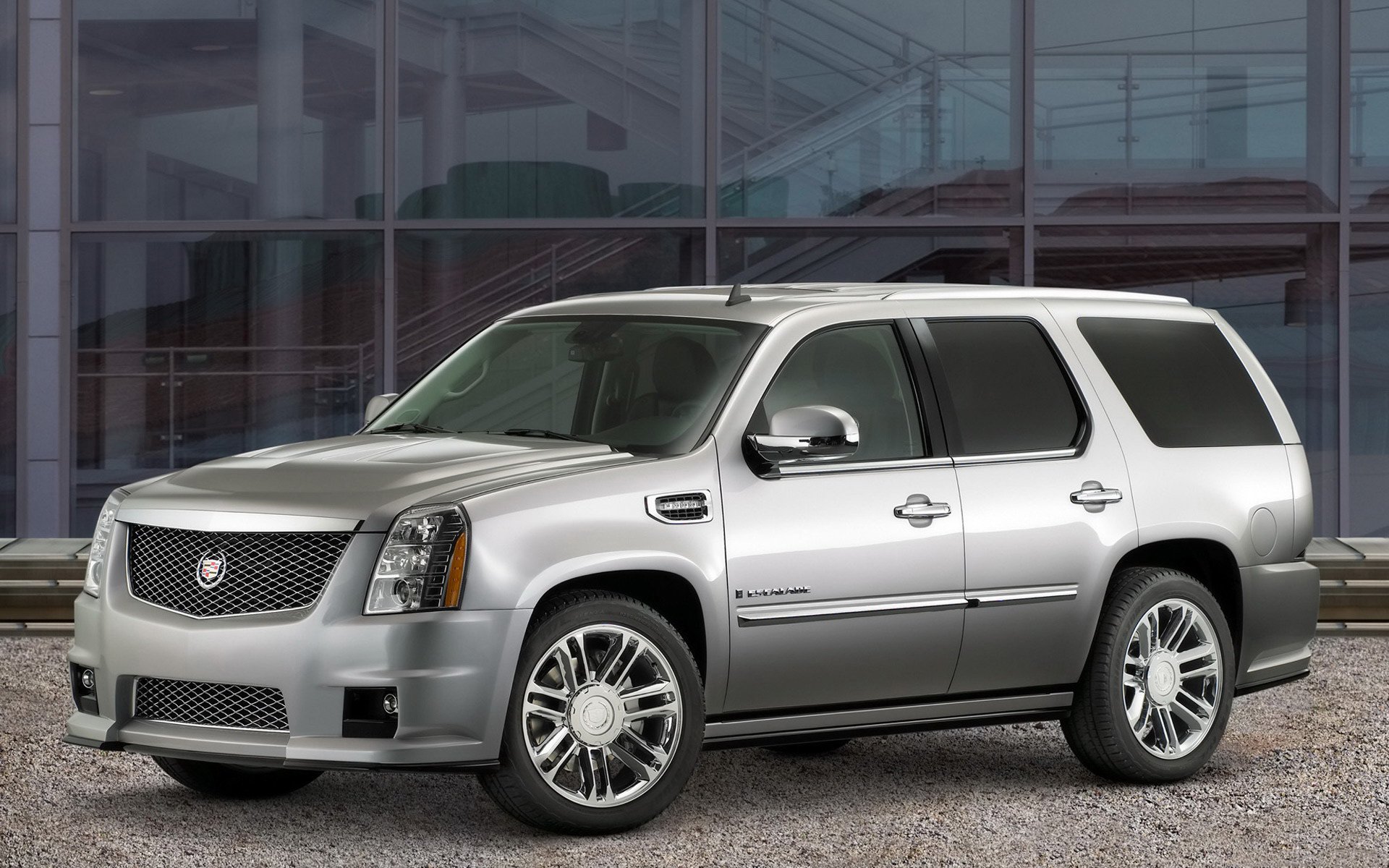 Silver Cadillac SUV parked in front of a modern glass building — HD PC desktop wallpaper and background