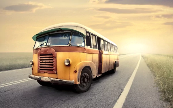 A vintage bus parked on a quiet road, bathed in warm sunset light, creating a serene atmosphere. This HD desktop wallpaper captures a nostalgic moment in time.
