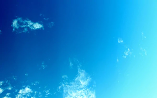 A serene HD wallpaper featuring a bright blue sky with scattered white clouds, capturing the beauty of nature and the vastness above.