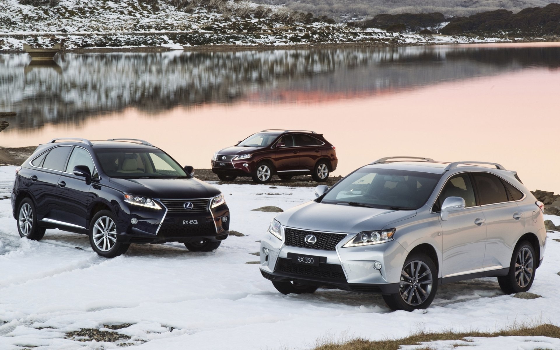 HD PC desktop wallpaper background: three Lexus vehicles (SUVs) parked on a snowy lakeshore with a pink sunset reflected in the calm water.