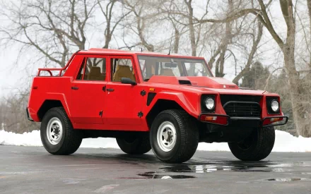 Red Lamborghini LM002 parked on wet pavement with snow and bare trees behind — HD PC desktop wallpaper/background.