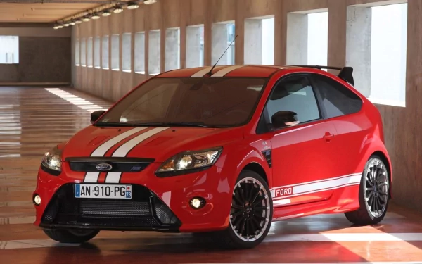 Red Ford Focus hatchback with white racing stripes parked in a sunlit garage — HD PC desktop wallpaper/background.