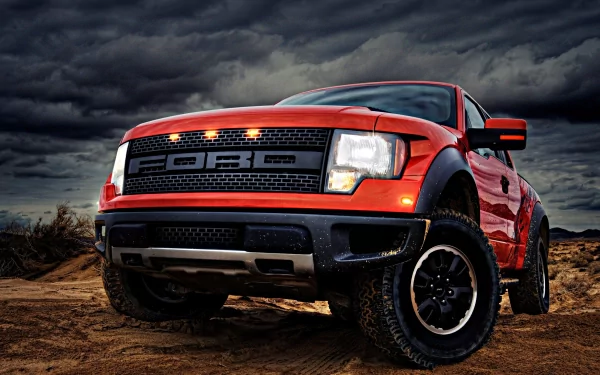 HD desktop wallpaper featuring a bold red Ford Raptor truck on rugged terrain under a dramatic cloudy sky.