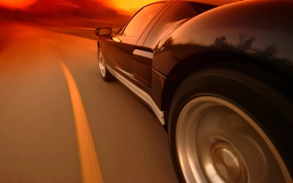 Low-angle, motion-blurred view of a black Ford GT vehicle racing at sunset — HD PC desktop wallpaper and background.