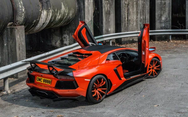 A stunning Lamborghini Aventador LP 700-4 with its doors open, showcasing its sleek design and vibrant orange color, set against an industrial background. High-definition wallpaper.