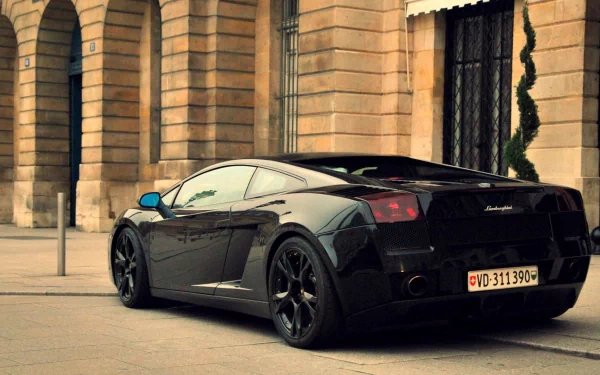 HD PC desktop wallpaper of a black Lamborghini Gallardo vehicle parked on a city street, sleek low profile and glossy finish against a stone-arched building backdrop.