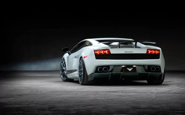 Rear three-quarter view of a white Lamborghini Gallardo Superleggera on a dim concrete floor, HD PC desktop wallpaper background.