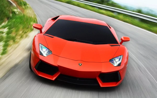 HD PC desktop wallpaper of a vibrant orange Lamborghini Aventador LP 700-4 speeding on a winding road with blurred background.
