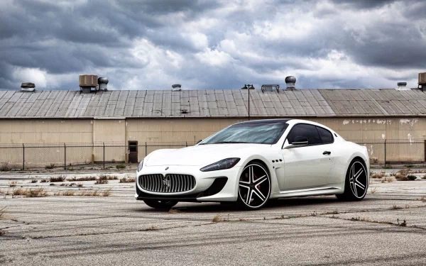 White Maserati sports vehicle on cracked tarmac beneath a dramatic cloudy sky — HD PC desktop wallpaper background