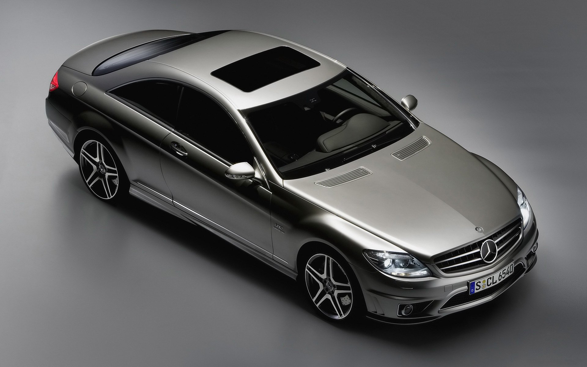 Sleek silver Mercedes coupe vehicle seen from a high angle on a gray background — HD PC desktop wallpaper and background highlighting its contours and sunroof.