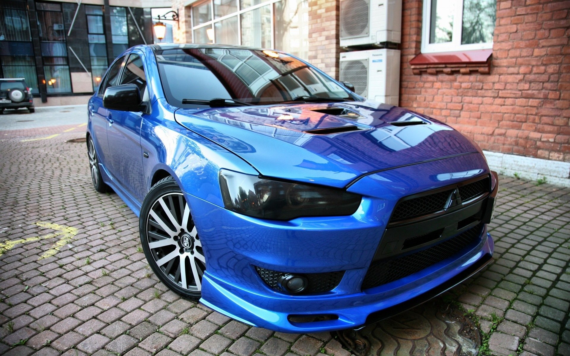 Blue Mitsubishi sedan parked on a cobblestone driveway with glossy finish and sporty front end — HD PC desktop wallpaper and background.
