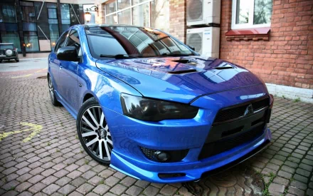 Blue Mitsubishi sedan parked on a cobblestone driveway with glossy finish and sporty front end — HD PC desktop wallpaper and background.