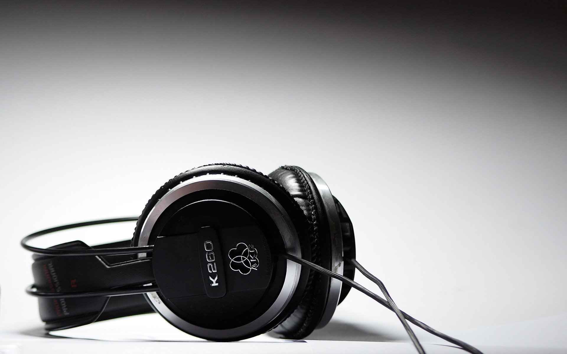 Black over-ear headphones with a cord rest on a white surface, captured in high definition for a music-themed PC desktop wallpaper.
